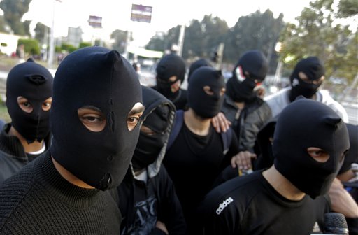 Egyptian masked protesters, who call themselves the black eagles and describes themselves as peaceful but are prepared to defend any attacks against protesters, gather near the presidential palace in Cairo, Egypt, Friday, Jan. 25, 2013. Two years after Egypt's revolution began, the country's schism was on display Friday as the mainly liberal and secular opposition held rallies saying the goals of the pro-democracy uprising have not been met and denouncing Islamist President Mohammed Morsi. (AP Photo/Amr Nabil)